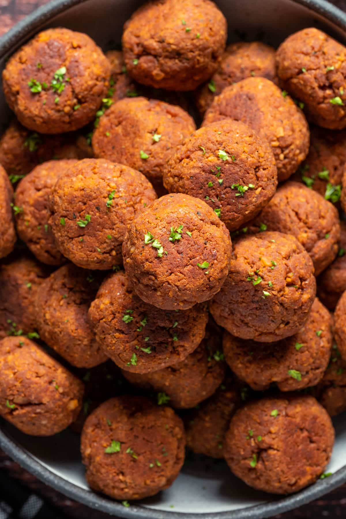 Meatballs stacked up on a plate.