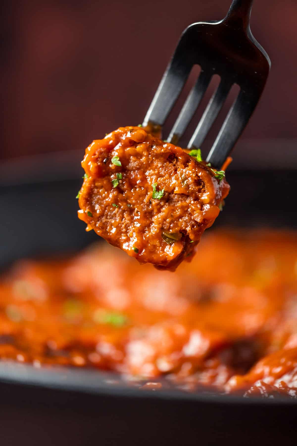 Vegan meatball in marinara sauce, sliced in half.