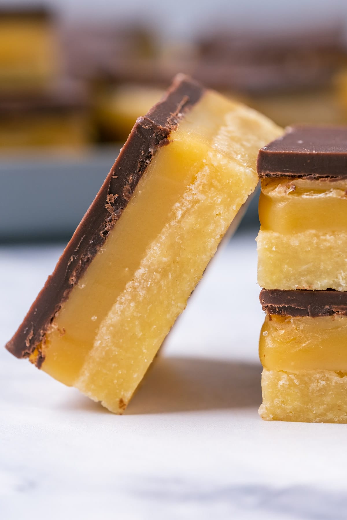 Vegan millionaire shortbread square leaning against a stack of millionaire shortbread.