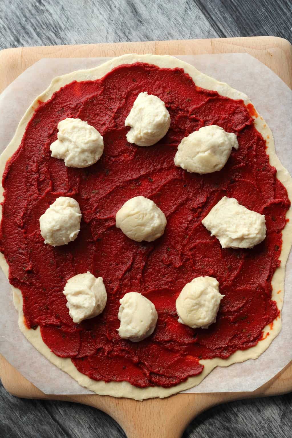 Vegan Mozzarella balls on top of a pizza ready to go into the oven. 