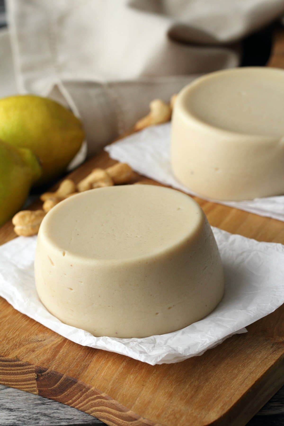 Vegan Mozzarella on parchment paper. Cashews and lemons in the background. 