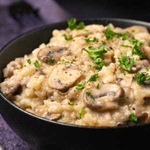 Vegan mushroom risotto in a black bowl.