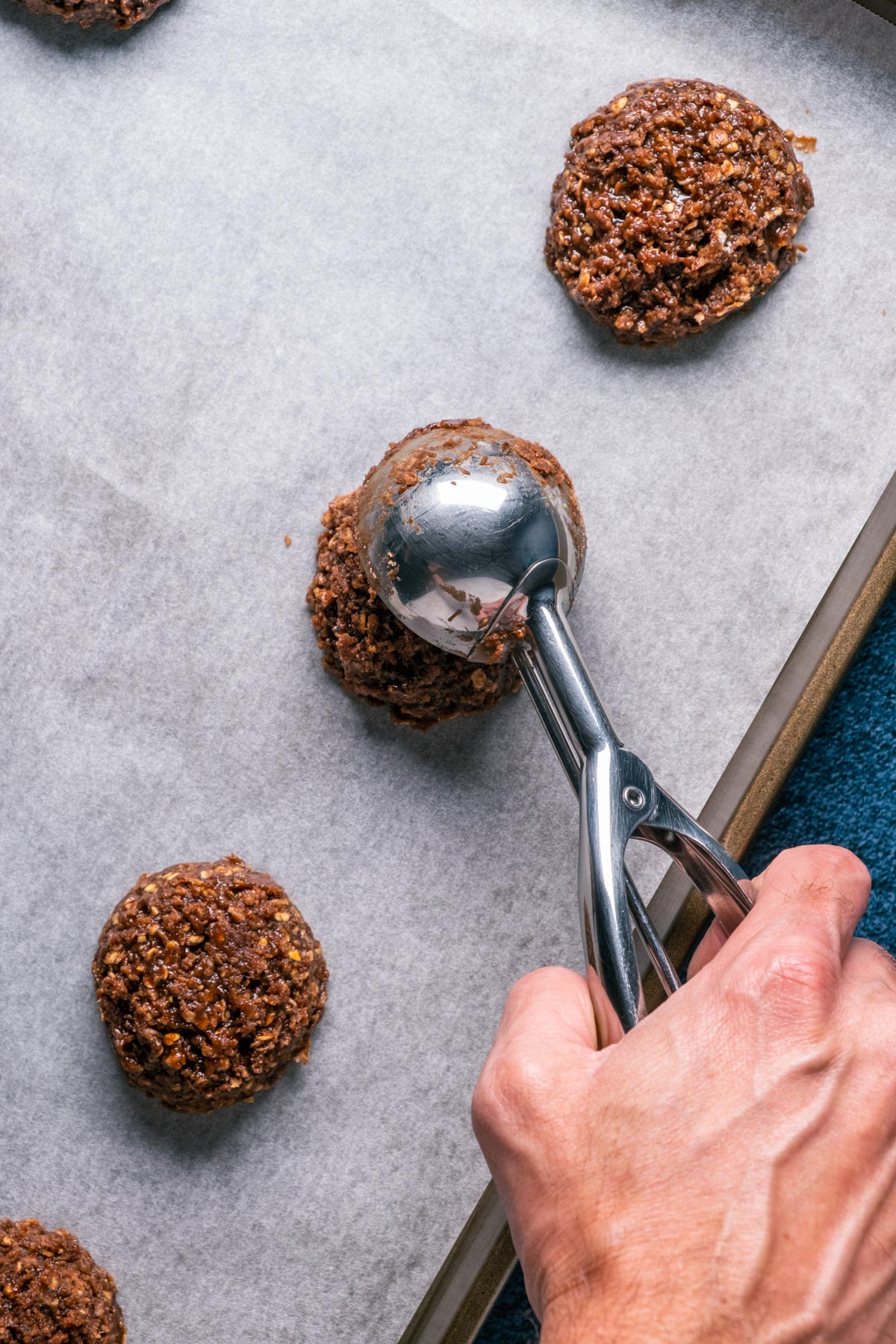 Scooping cookies out onto a parchment lined baking sheet.