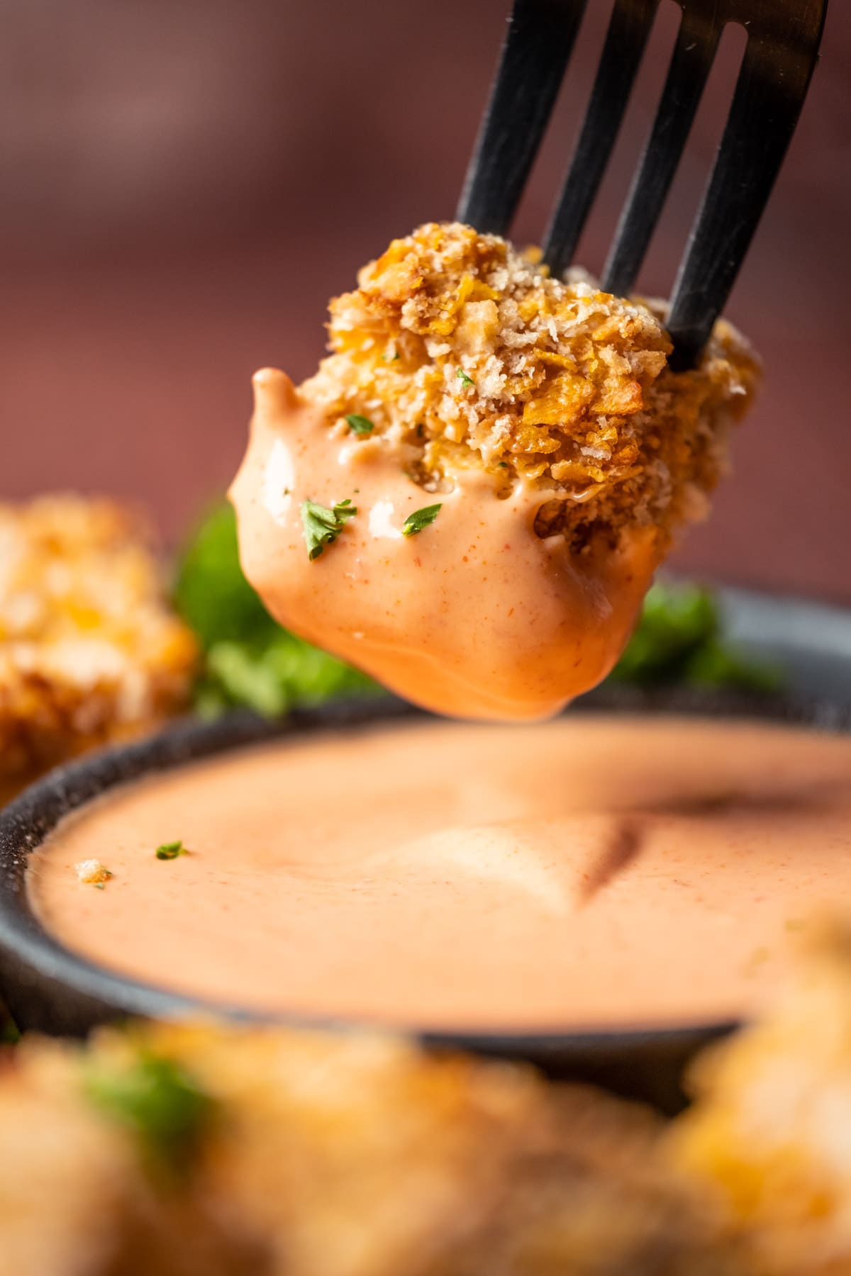 Vegan chicken nugget on a fork, dipped in yum yum sauce.