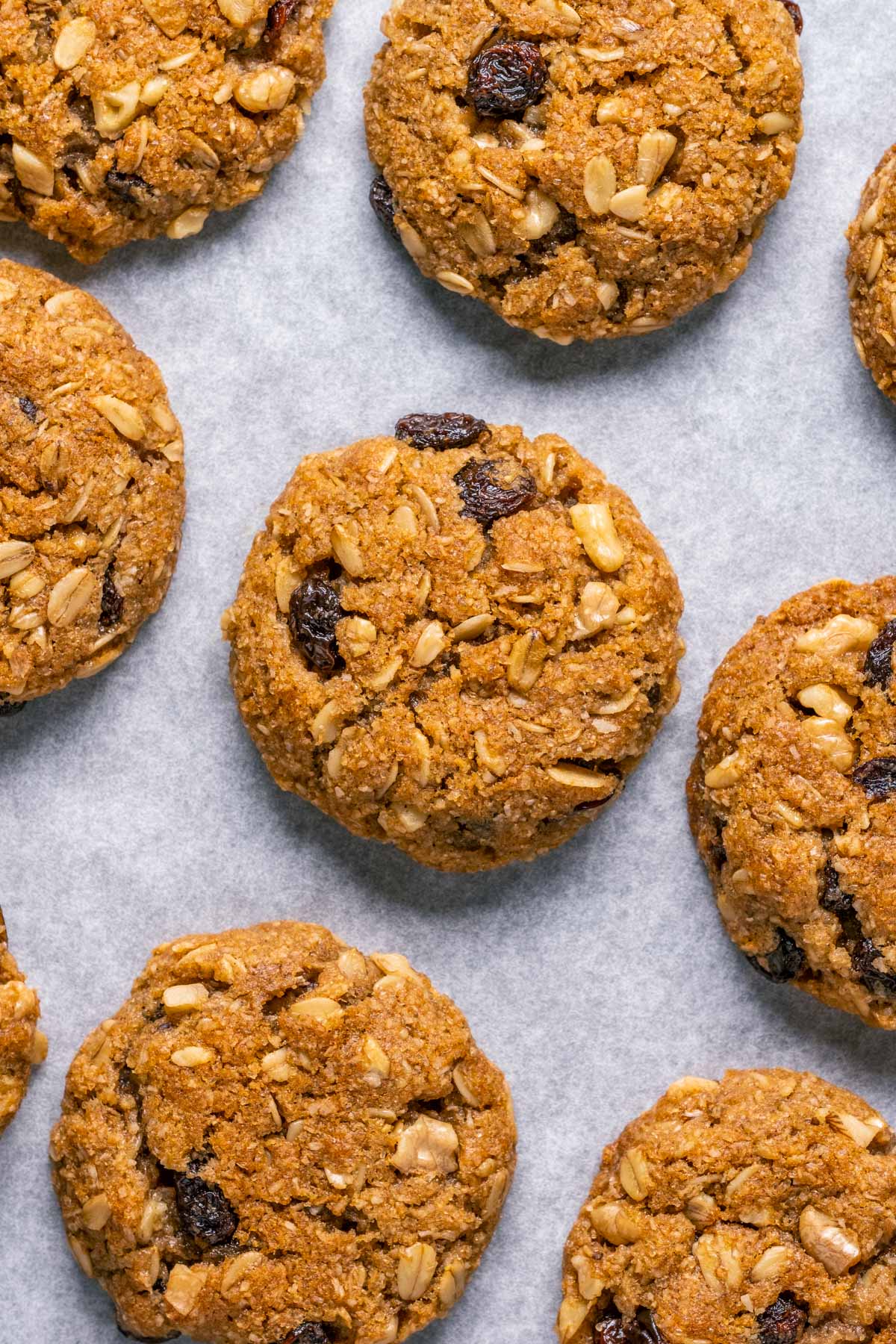 Vegan oatmeal raisin cookies on a parchment lined baking tray.