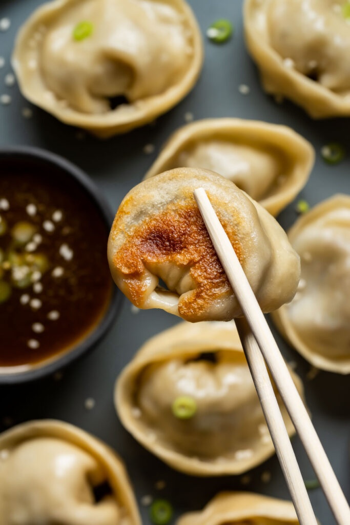 Chopsticks holding a dumpling.