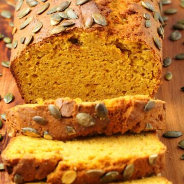 Sliced loaf of vegan pumpkin bread on a wooden board.