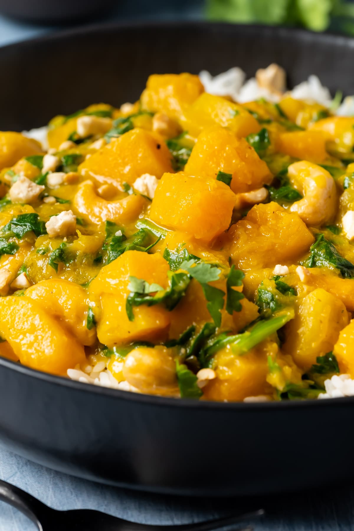 Thai pumpkin curry with rice in a black bowl.