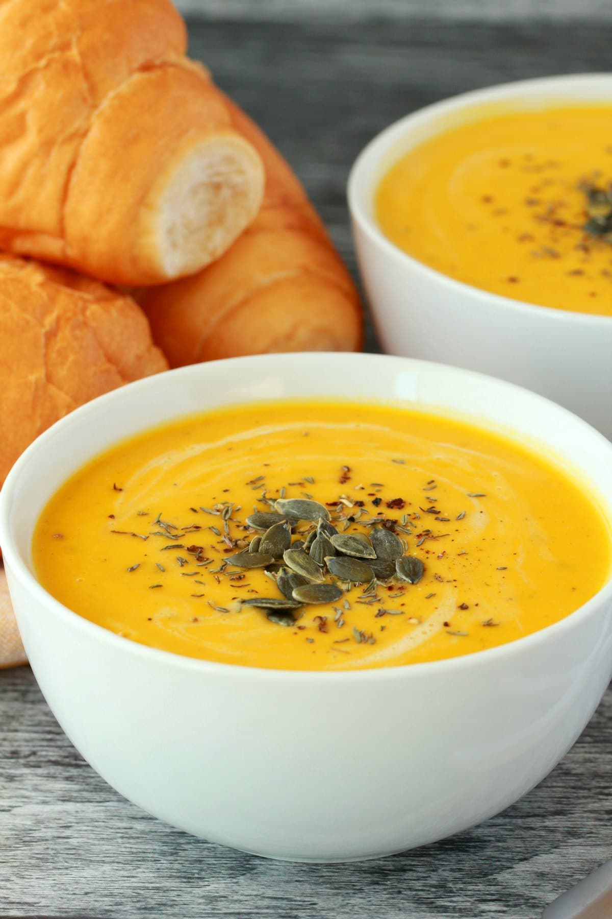 Vegan pumpkin soup topped with pumpkin seeds in a white bowl. 