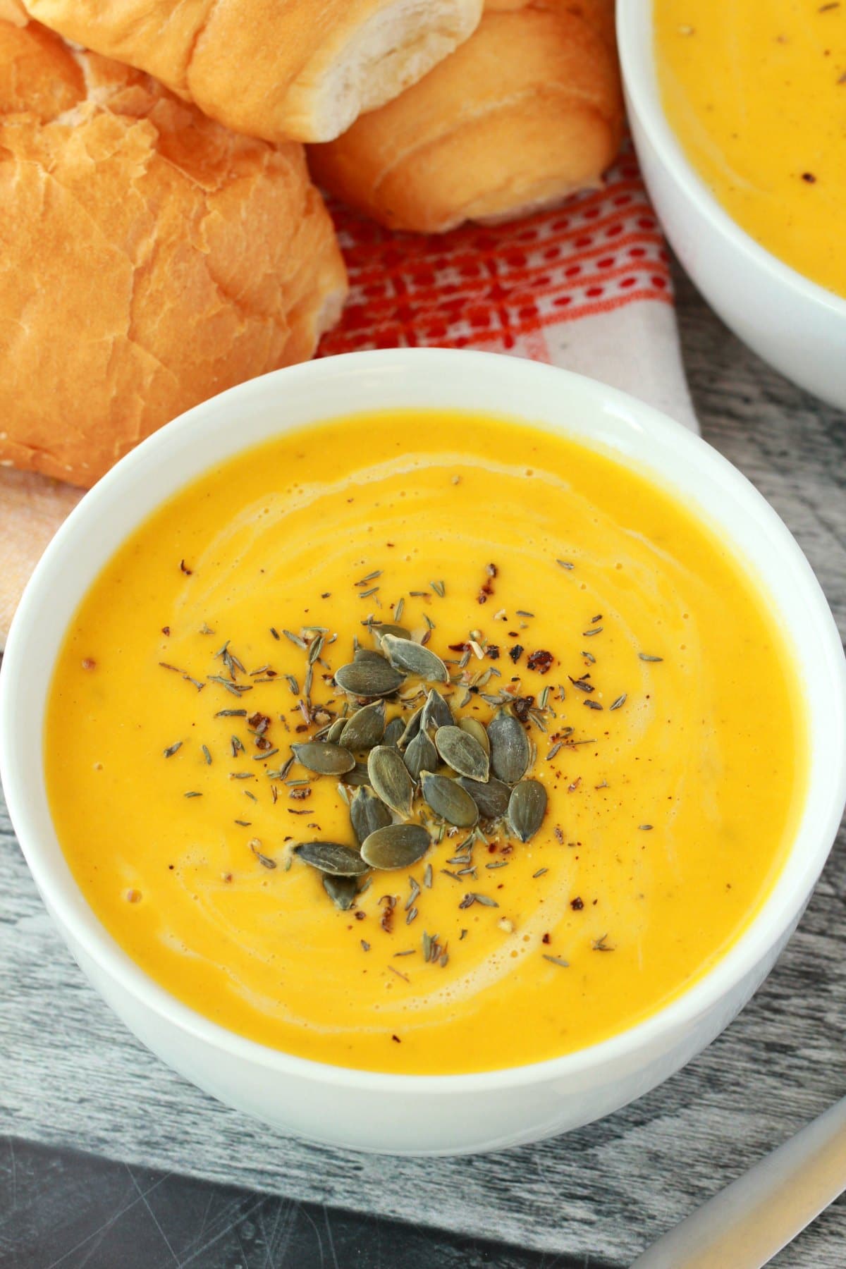 Vegan pumpkin soup in a white bowl with pumpkin seeds. 