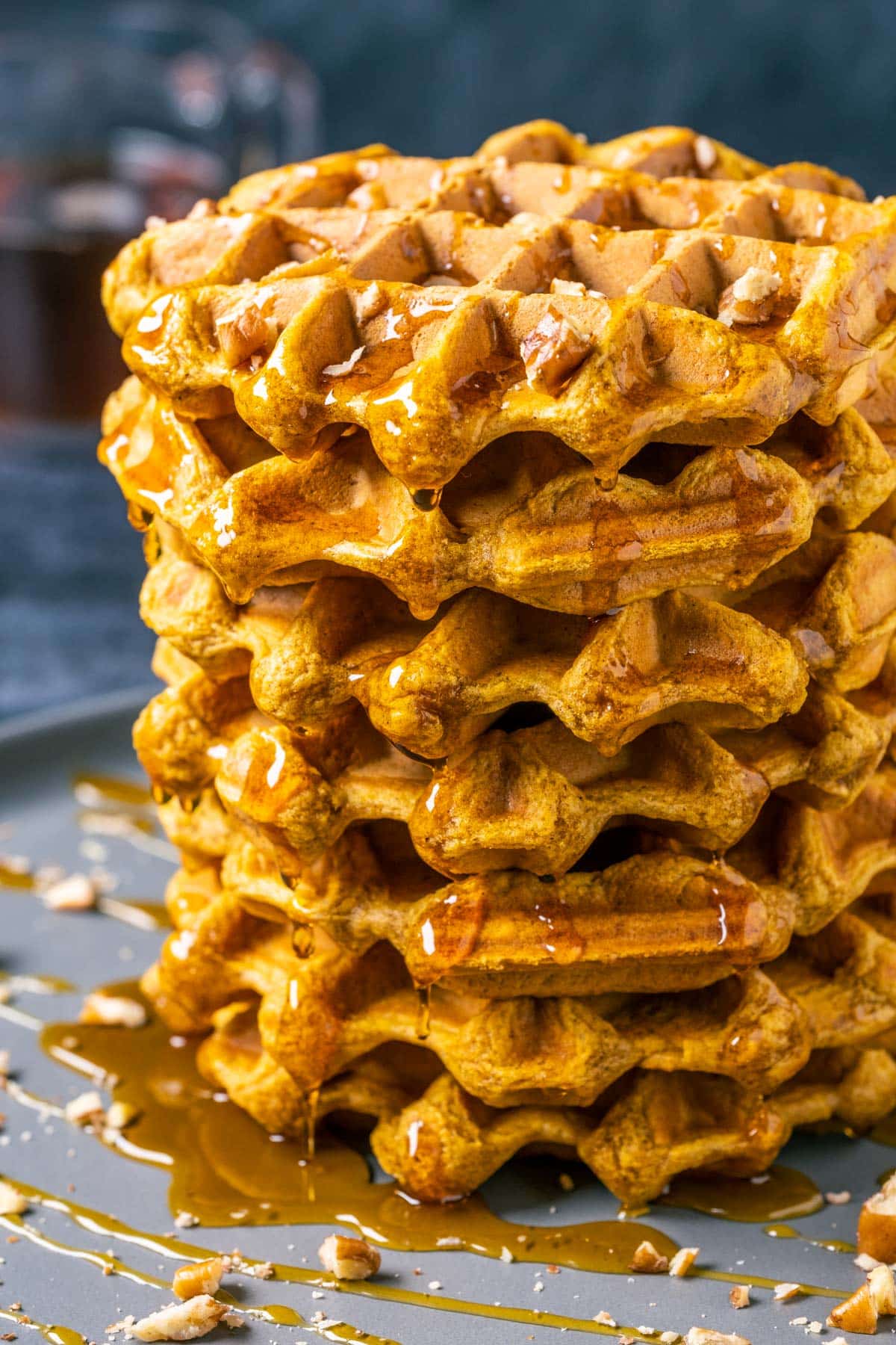 Waffles with syrup and pecans on a gray plate.