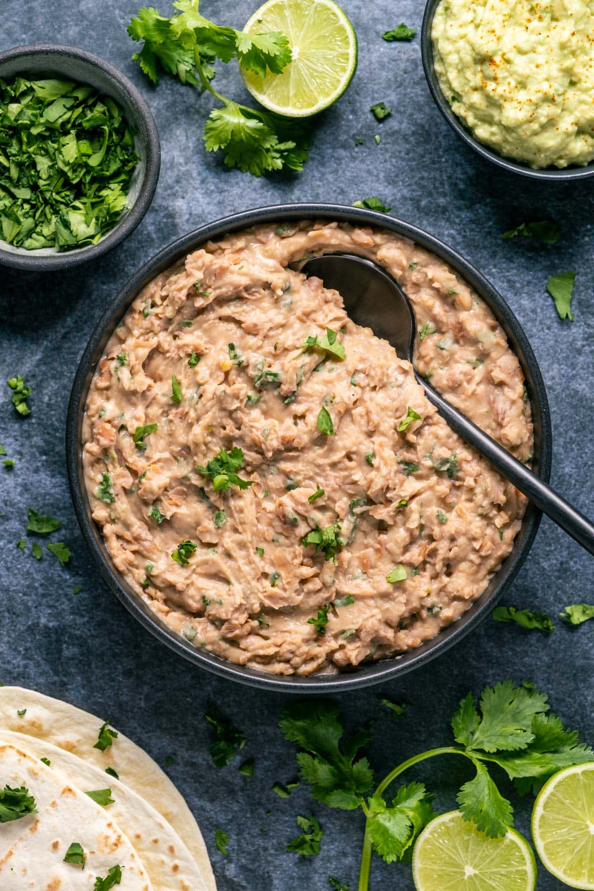 Vegan refried beans in a black bowl with a spoon. 