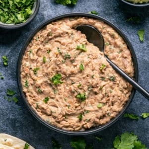 Vegan refried beans in a black bowl with a spoon.