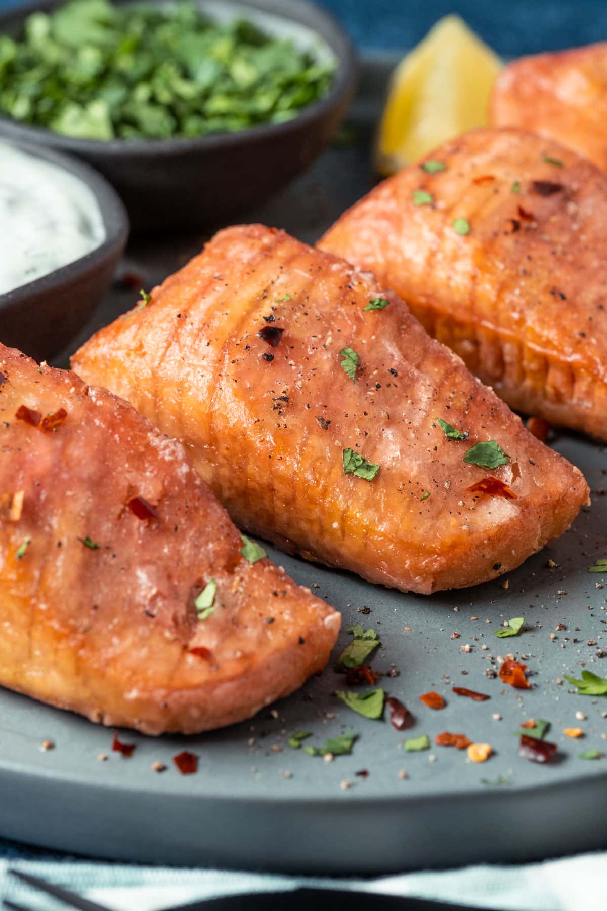 Vegan salmon on a plate with lemon wedges, tartar sauce and chopped cilantro. 