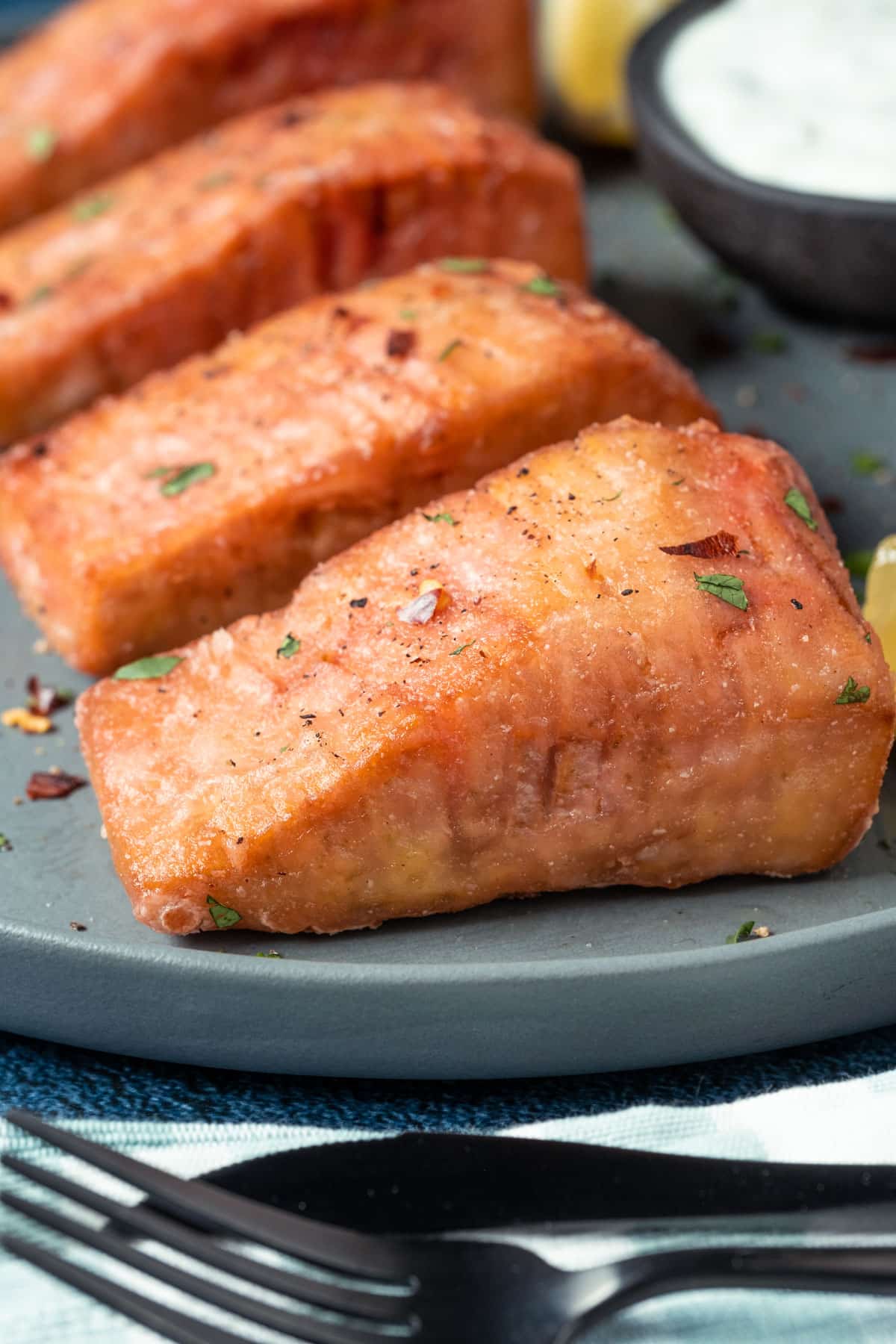 Vegan salmon on a plate with lemon wedges, tartar sauce and chopped cilantro.