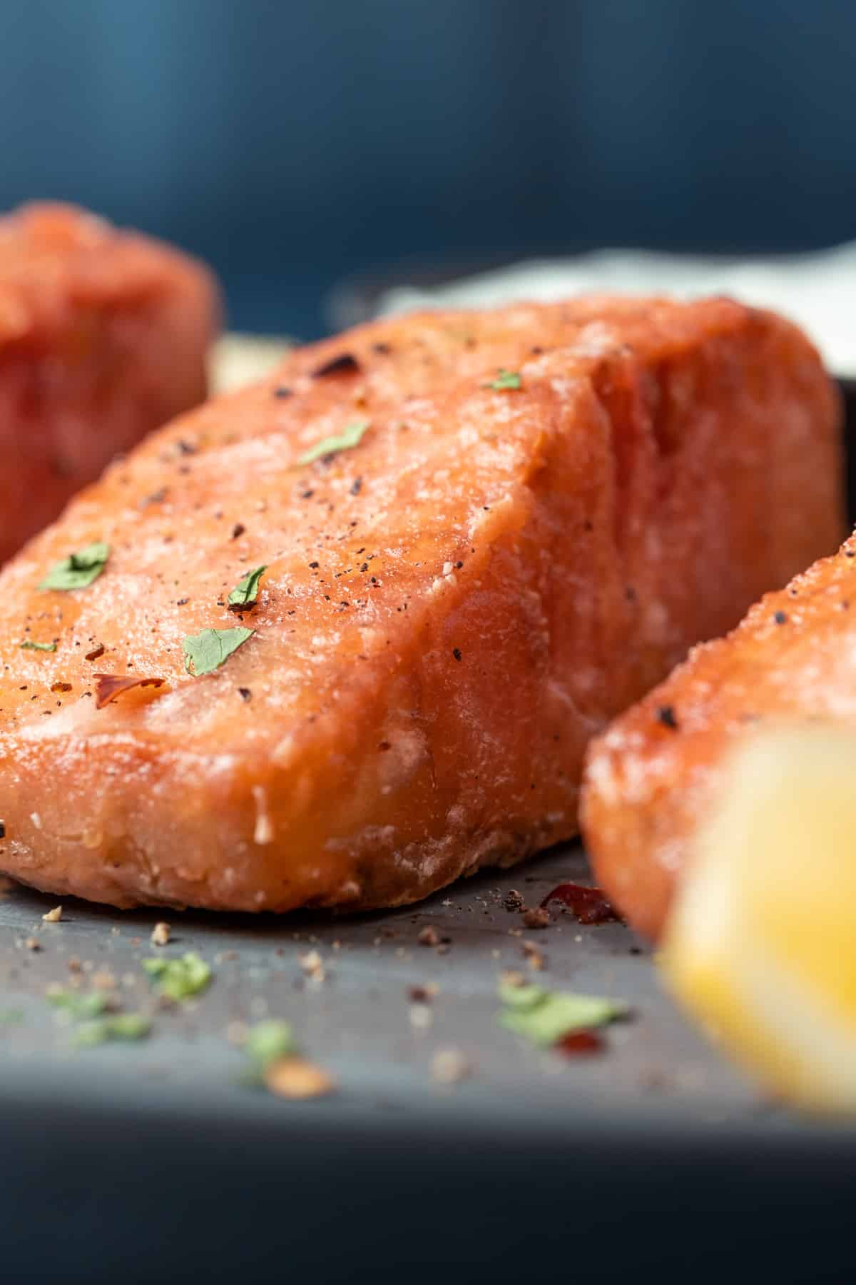 Vegan salmon on a plate with lemon wedges, tartar sauce and chopped cilantro.