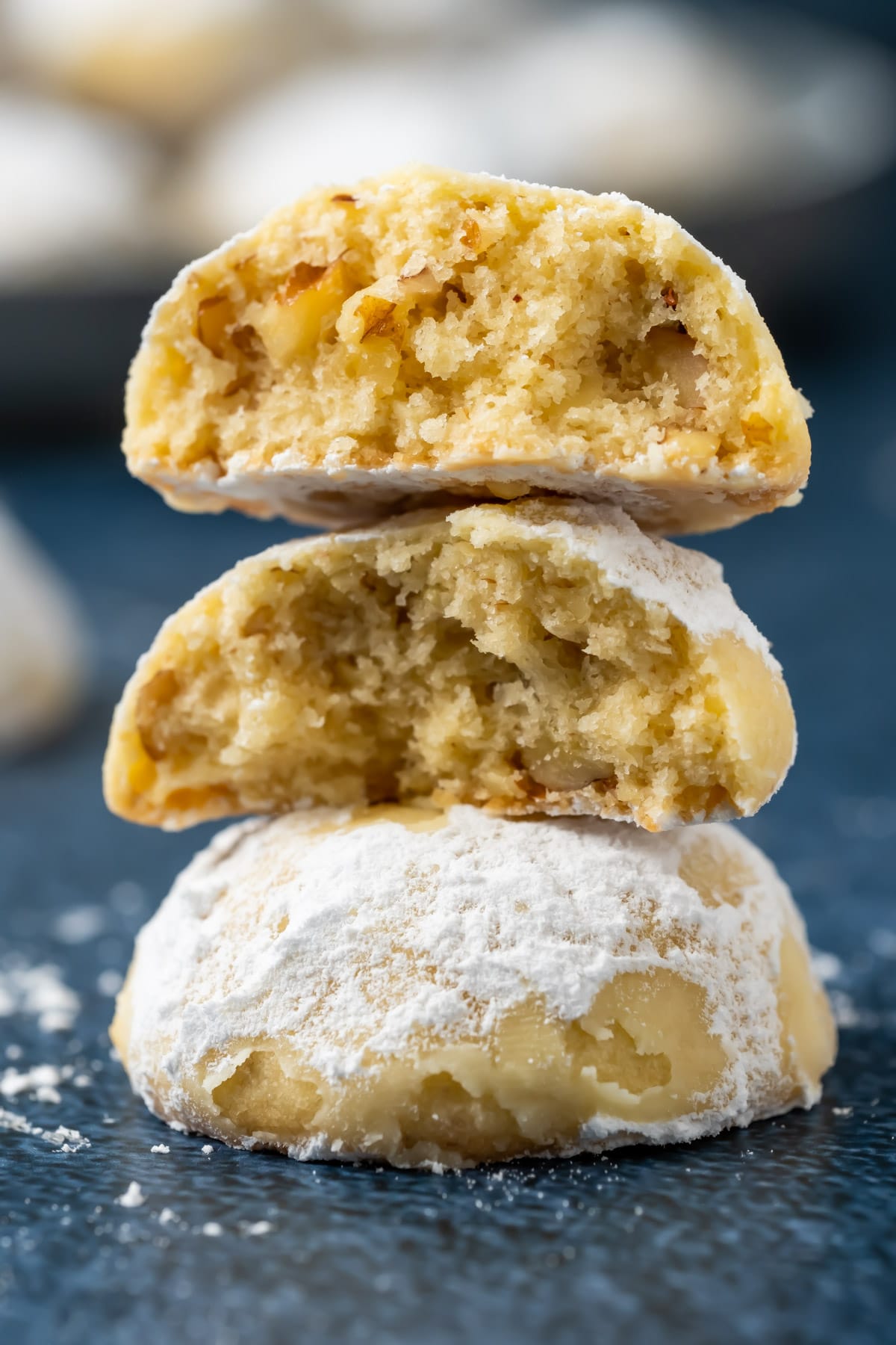 Vegan snowball cookies in a stack with the top cookie broken in half.