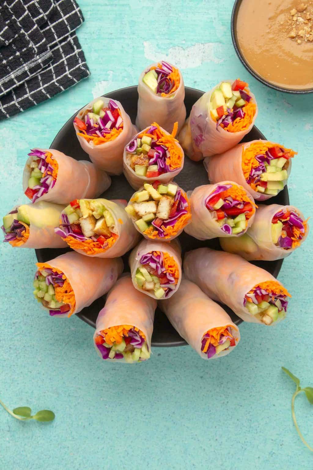 Vegan summer rolls standing upright in a black bowl. 