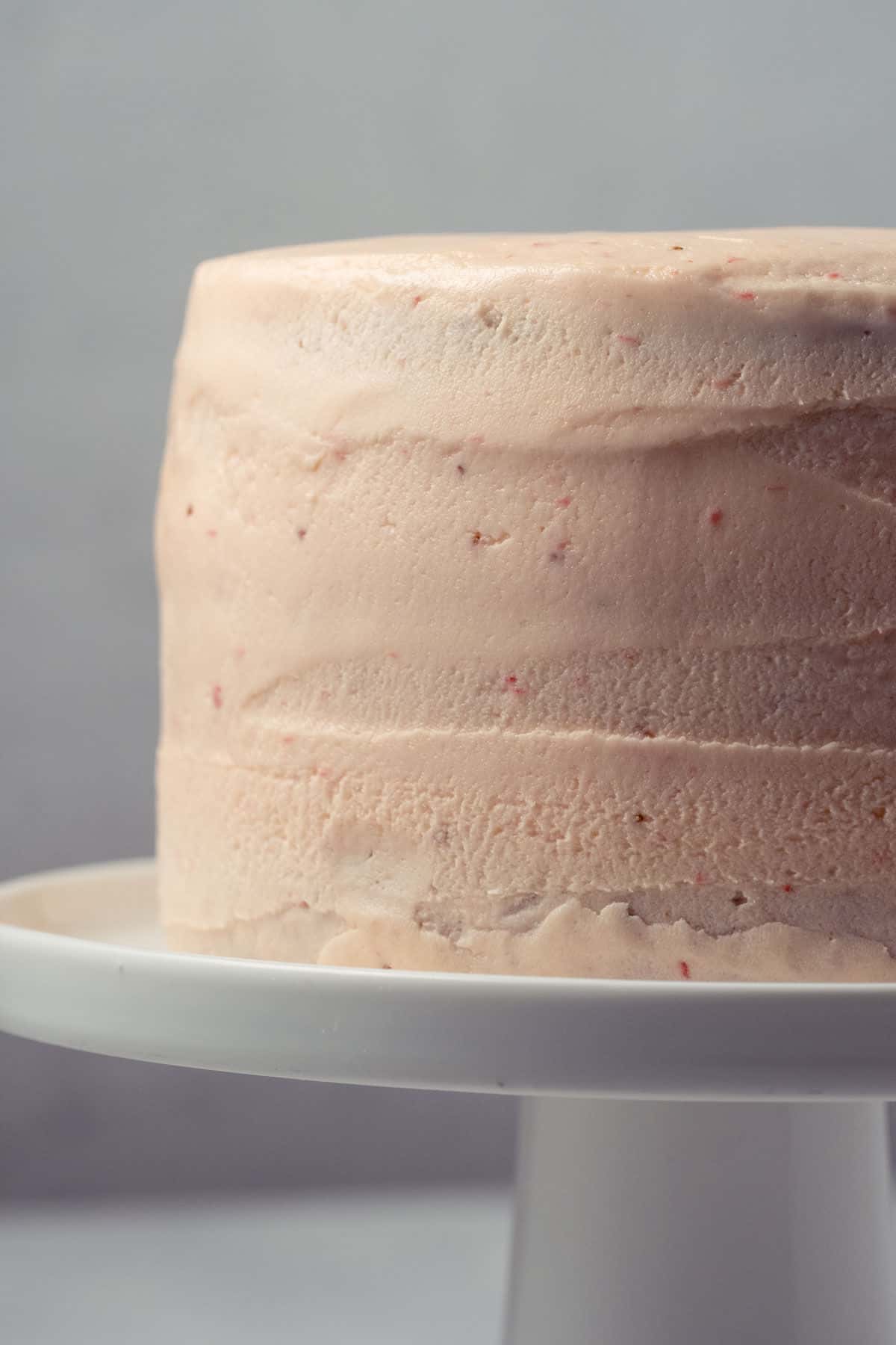 Strawberry cake on a white cake stand.