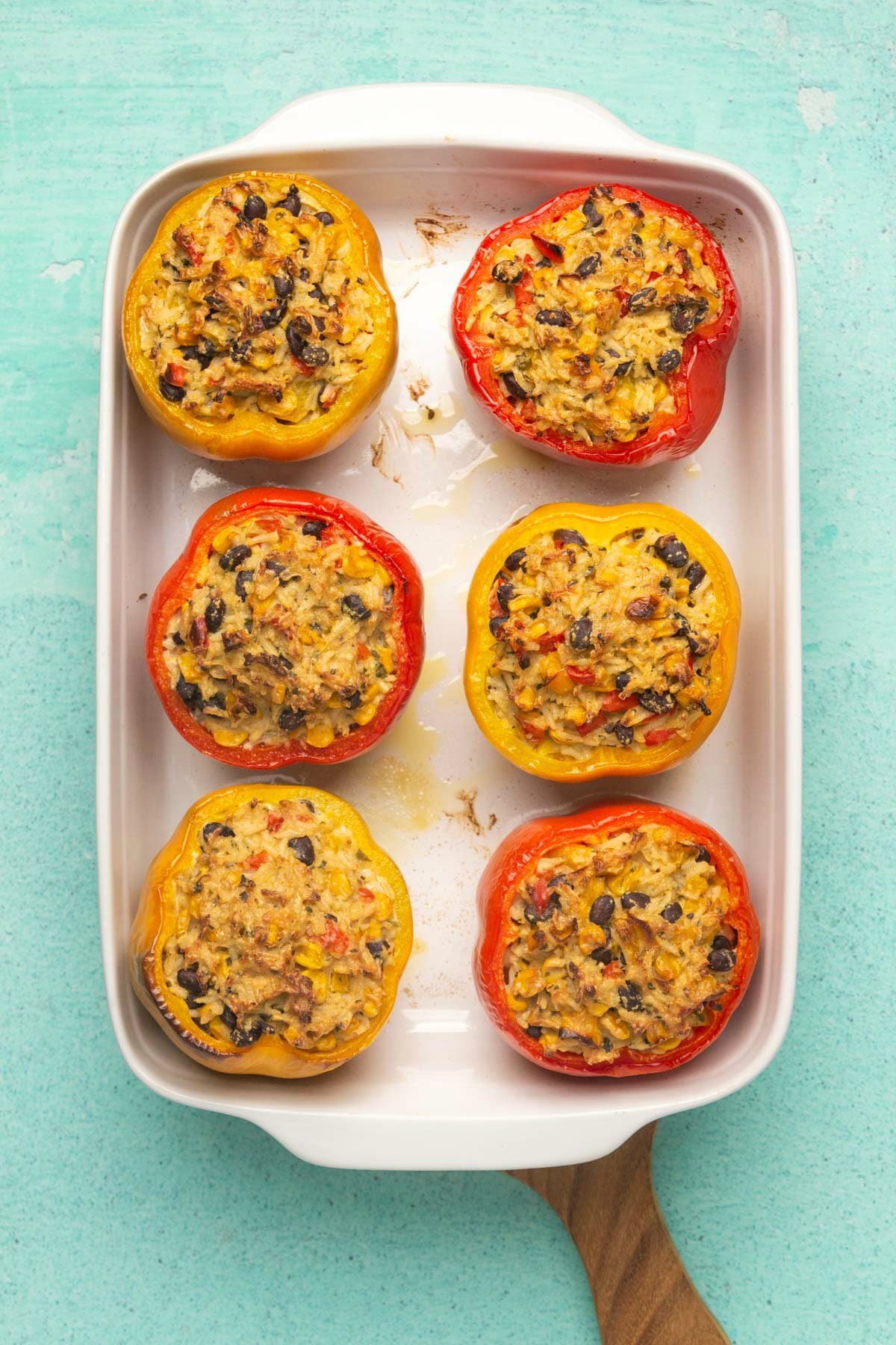 Freshly baked vegan stuffed peppers in a white baking dish. 