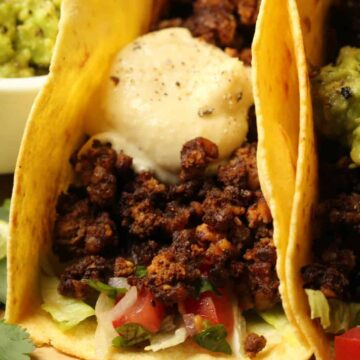 Vegan taco meat on a fully loaded taco on a wooden board.