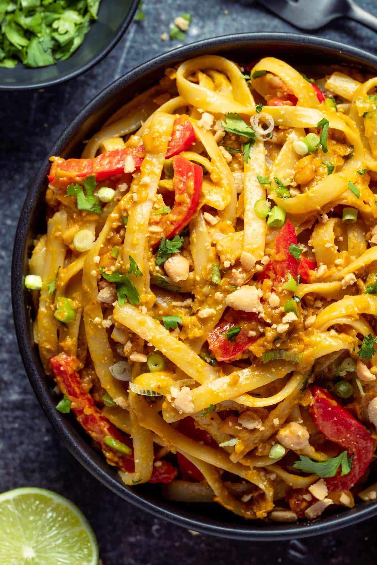 Vegan Thai Peanut Noodles in a black bowl with lime wedges.