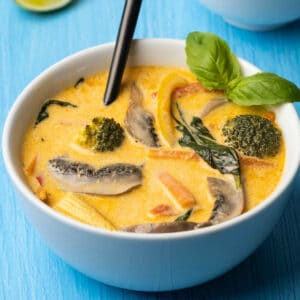 Vegan Thai red curry in a white bowl with a spoon.