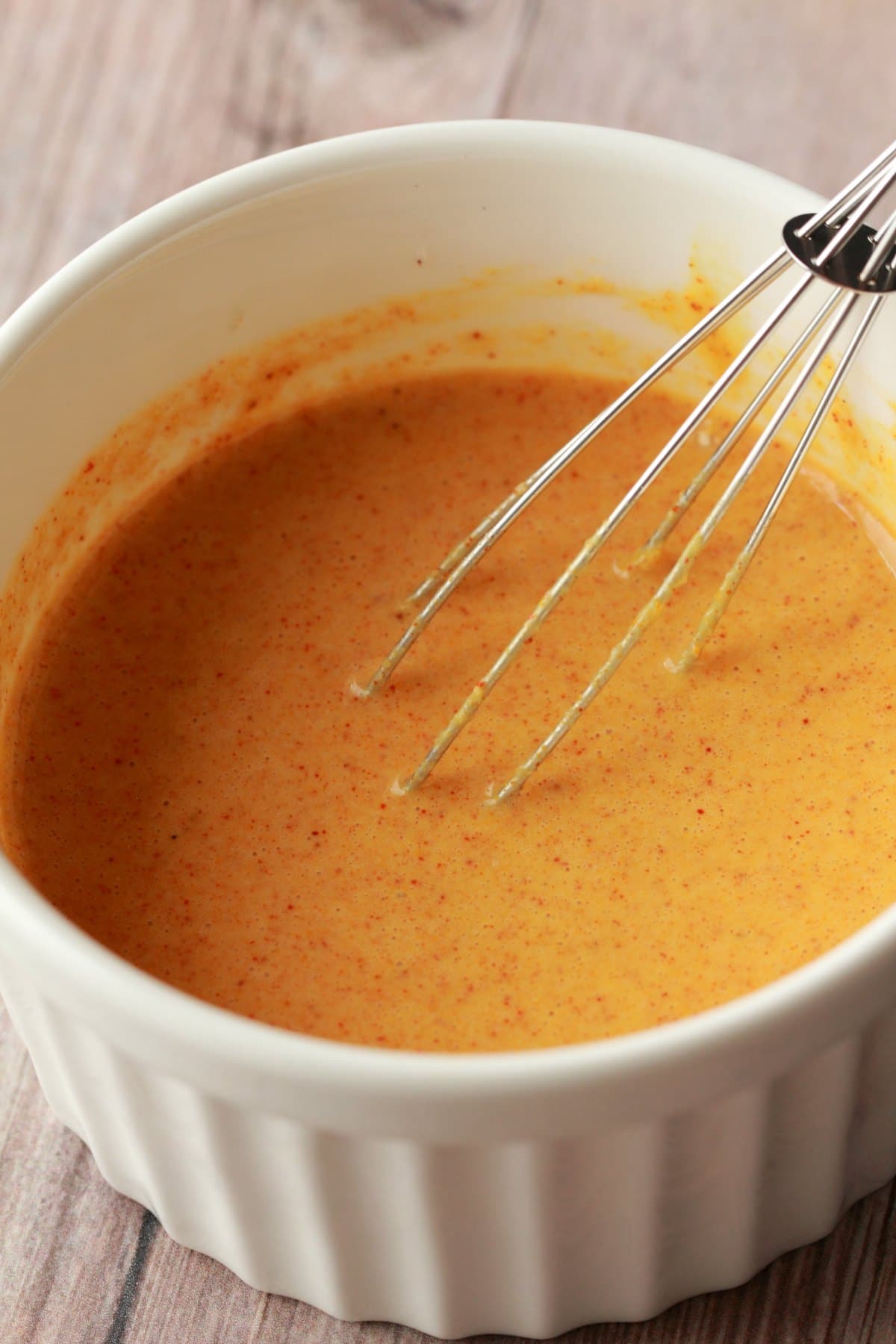 Tofu scramble sauce in a white bowl with a whisk. 