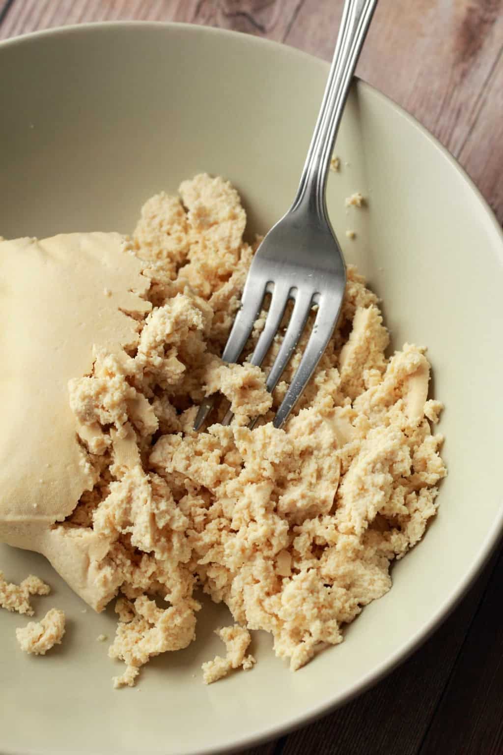 Mashing tofu with a fork.