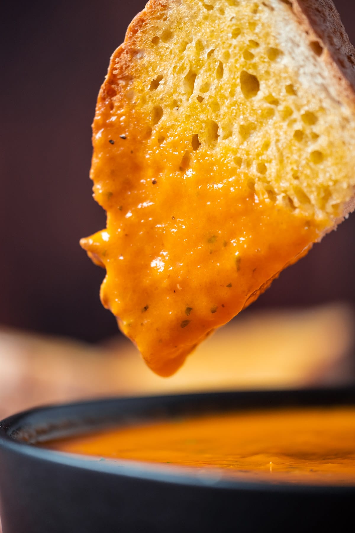 Bread dipped in a bowl of vegan tomato soup.