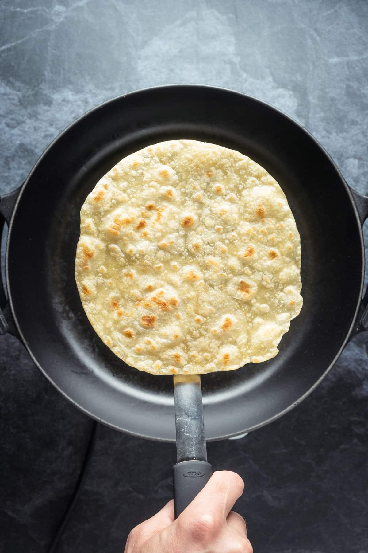 Vegan tortilla lifted up on a spatula.