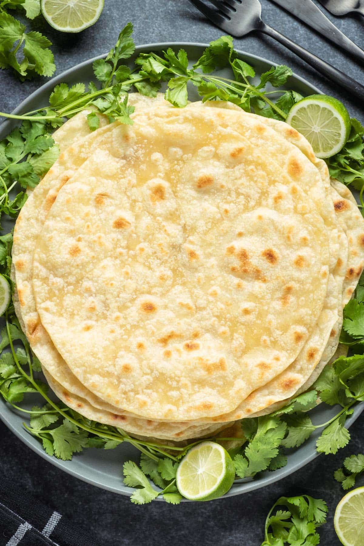 Stack of vegan tortillas on a plate with fresh cilantro. 