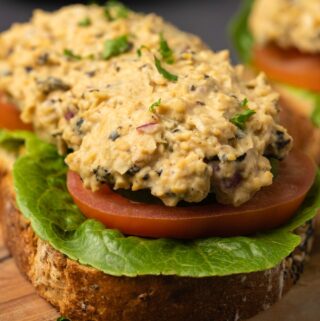 Vegan tuna on an open faced sandwich on a wooden board.