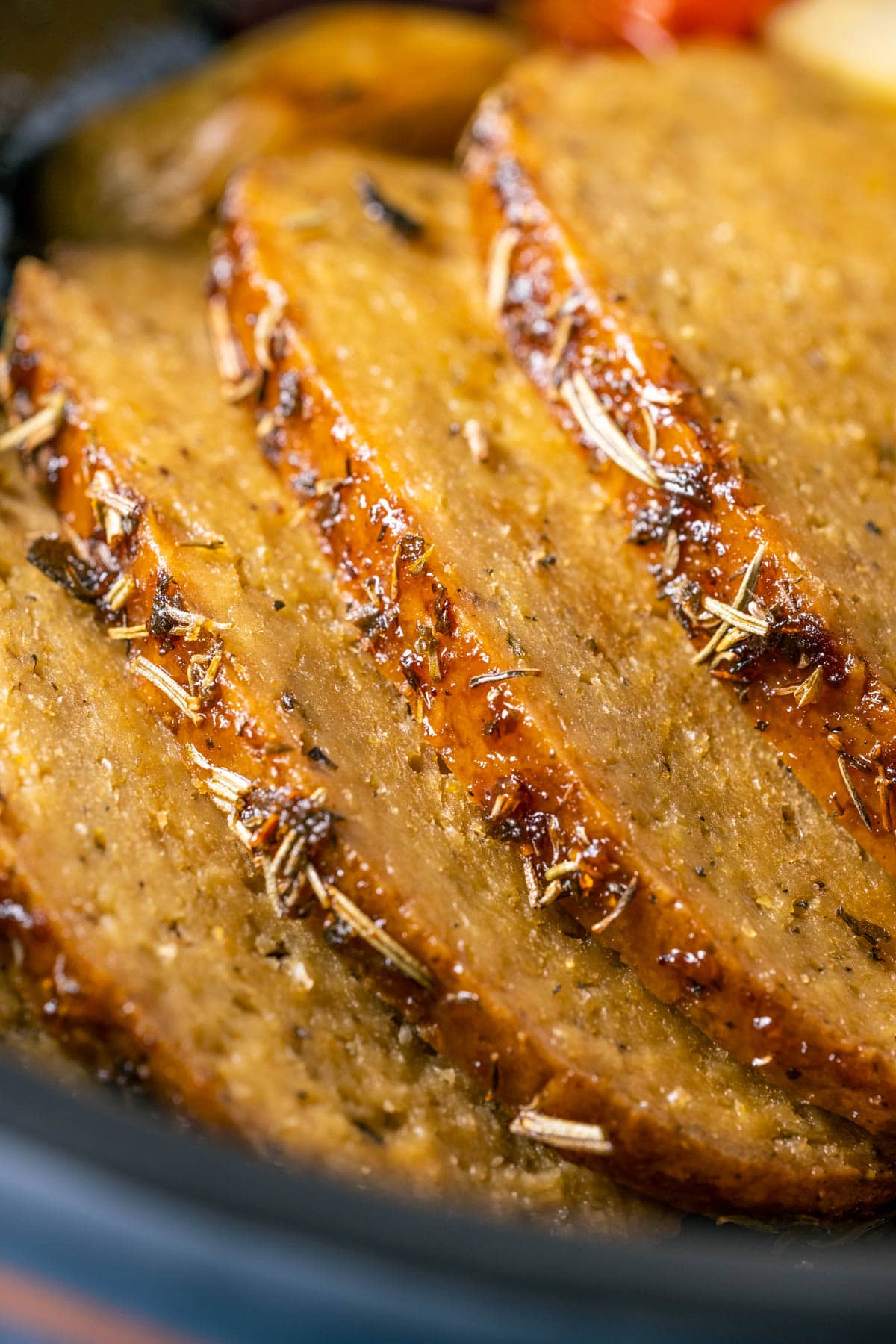 Slices of vegan turkey roast in a roasting pan.