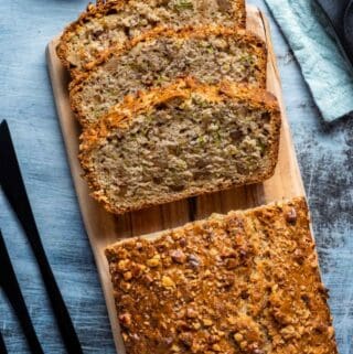 Sliced loaf of vegan zucchini bread on a wooden board.