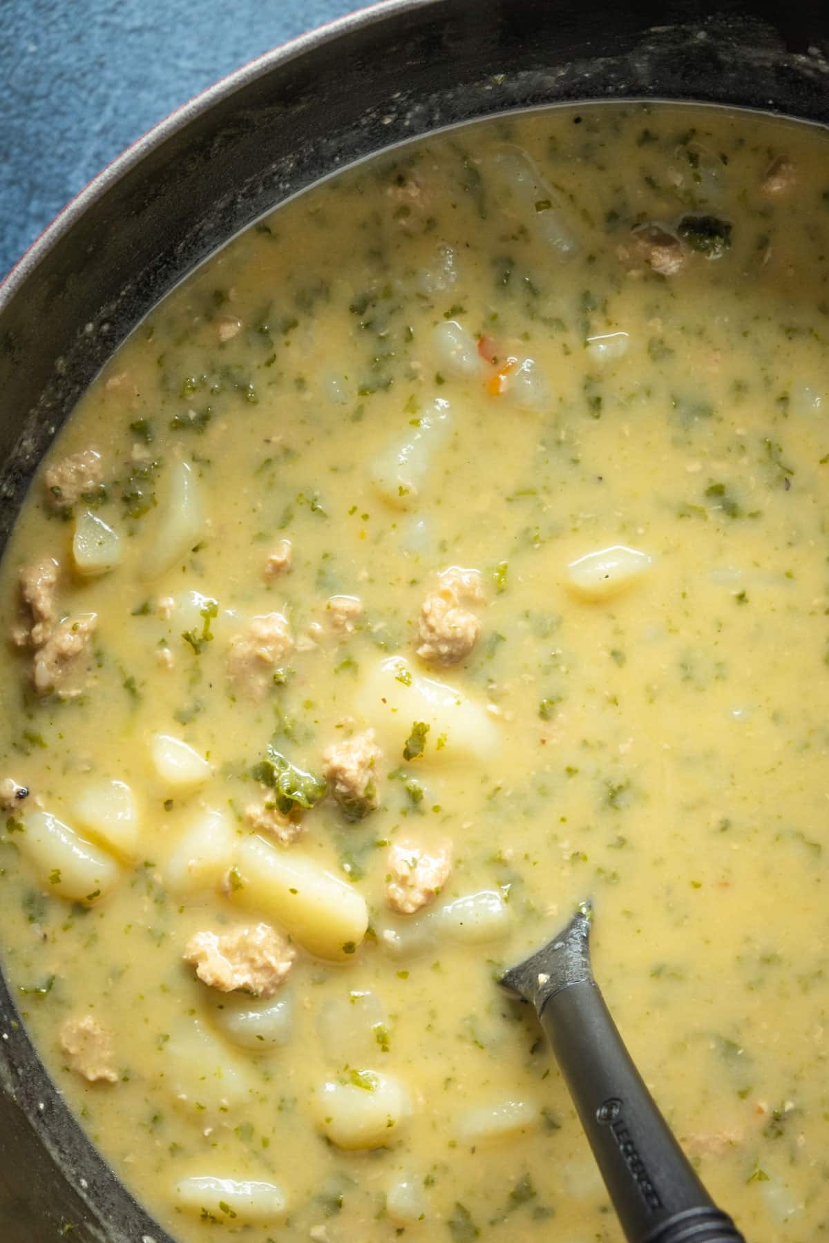 Vegan zuppa toscana in a pot with a soup ladle.