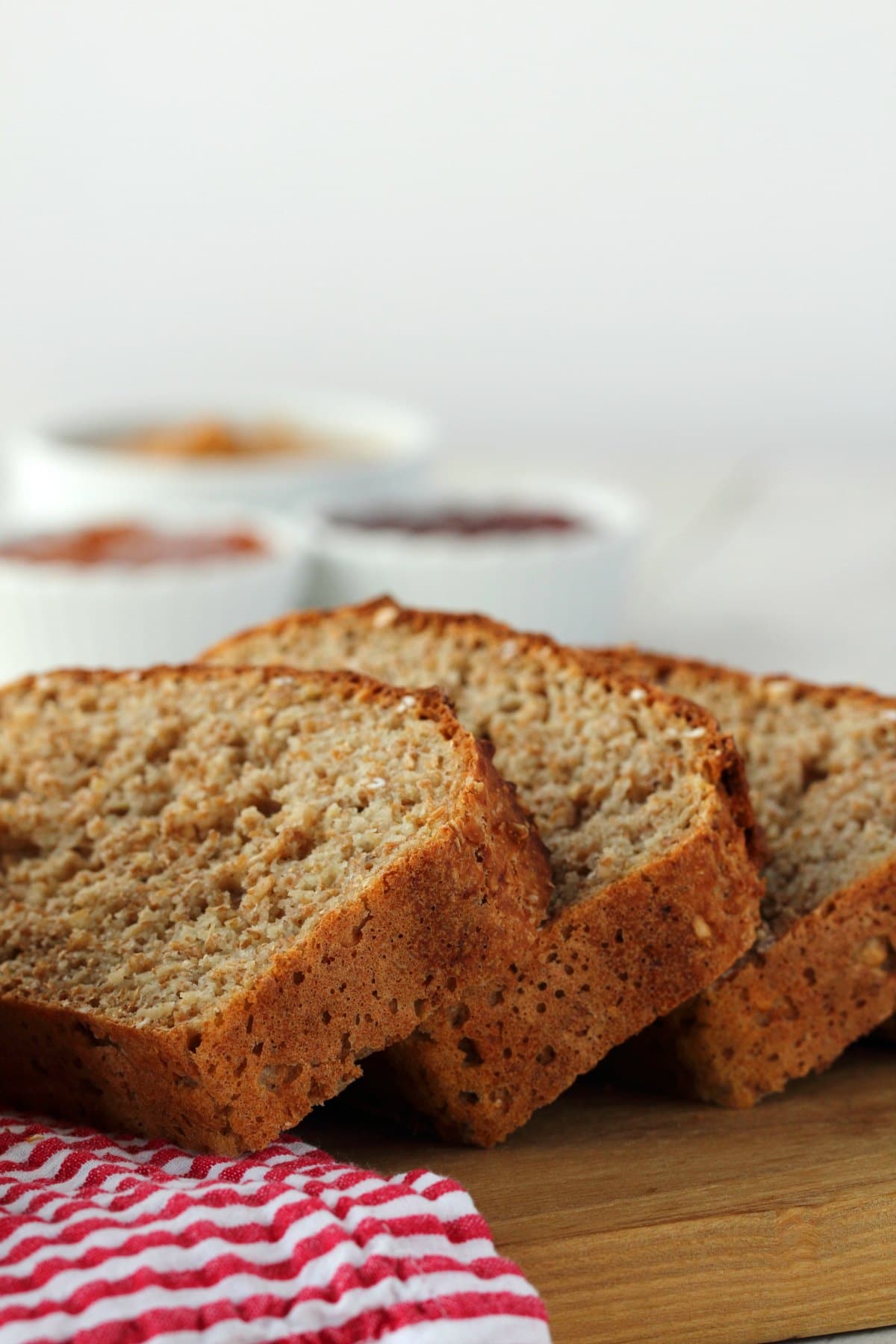 Slices of Wholewheat Bread on a wooden board with a red and white napkin. 